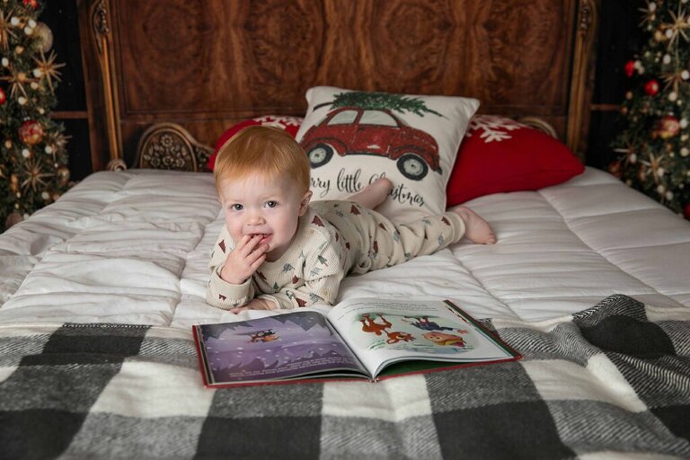 little boy in holiday pajamas reading a Christmas book